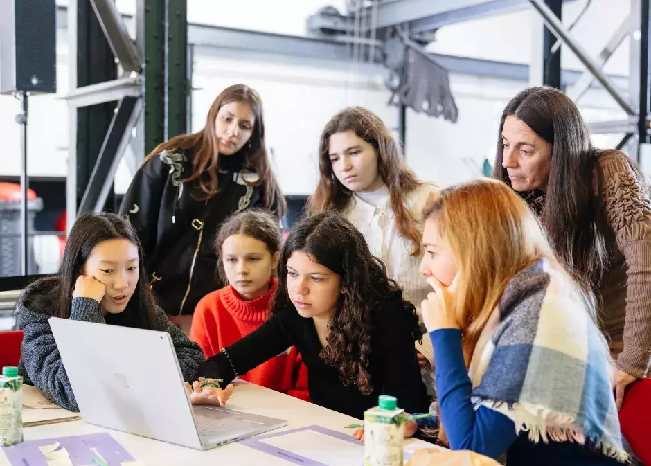 students and teachers working together around a computer